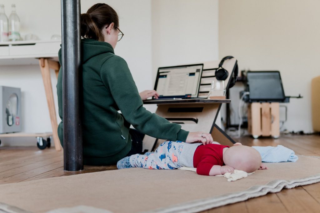 Mother working from home - at flexible and height-adjustable desk with baby.
